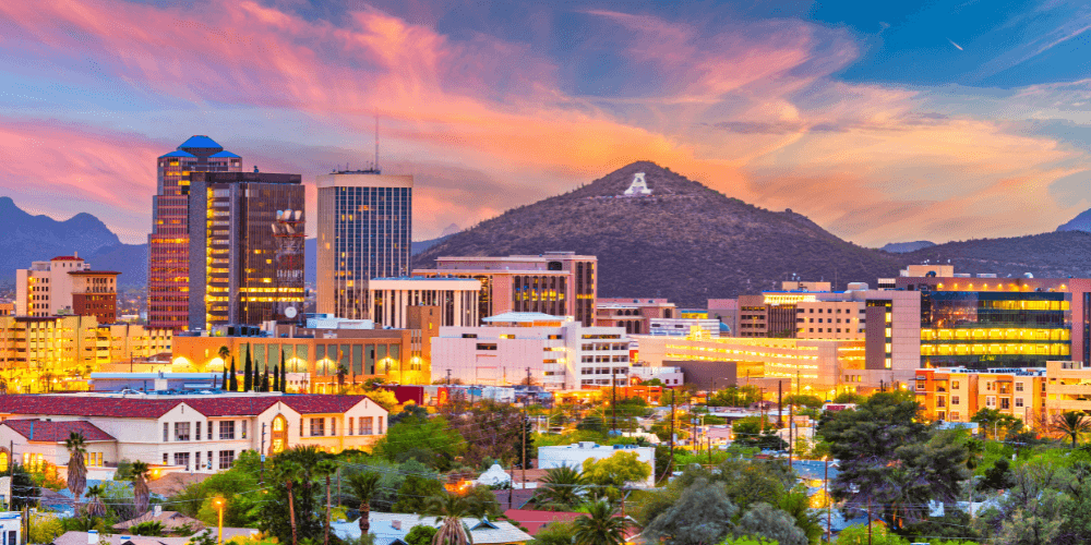 Panoramic view of Tucson, Arizona skyline against a clear blue sky, featuring prominent buildings and mountains in the background.